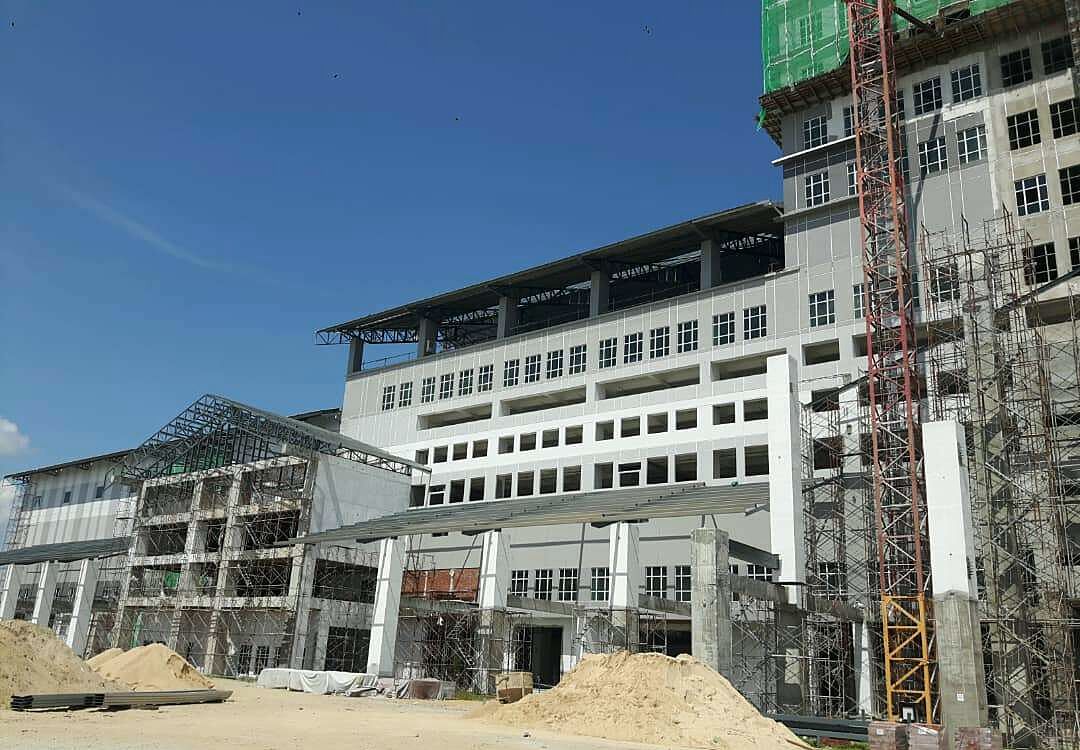 Multi-storey administrative building under construction with scaffolding and a tower crane
